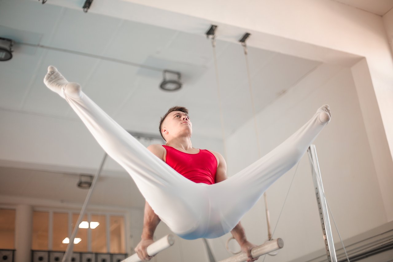 about-img A skilled male gymnast demonstrates control and strength on gymnastic rings indoors.
